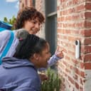 Google Nest Doorbell (battery) mounted on a brick wall beside a front door